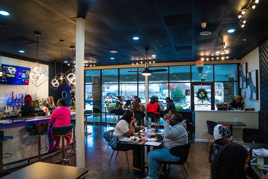 Modern restaurant interior featuring a blue-lit bar and dining area.
