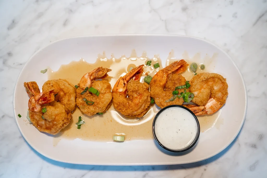 Five golden-brown fried shrimp with sauce, chives, and dipping sauce.