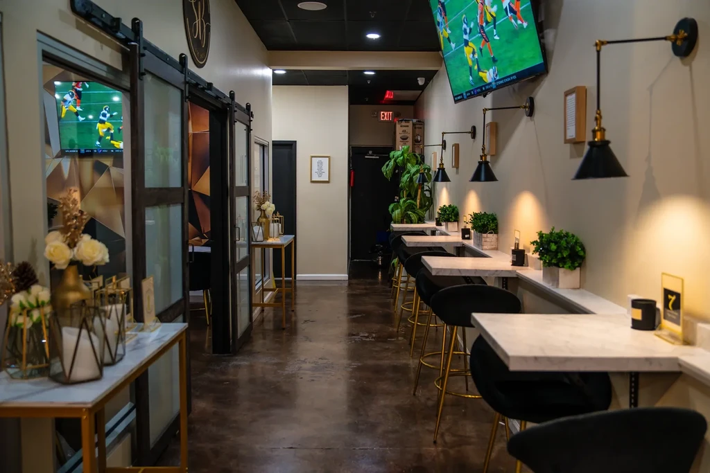 Sleek modern restaurant interior with marble, gold, and football on TVs.
