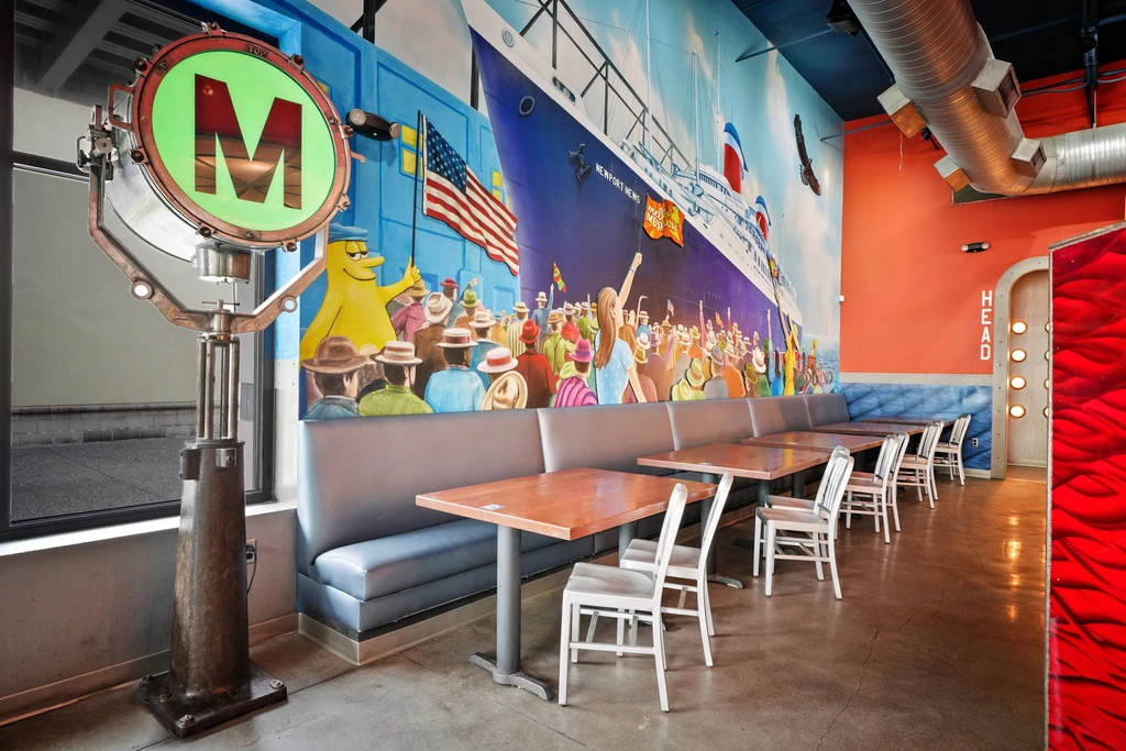 Restaurant interior with "Newport News" ship mural and retro spotlight.