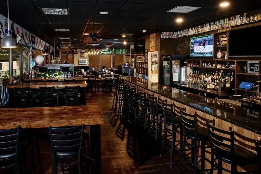 Interior of a casual sports bar; long bar, TVs, and dining.