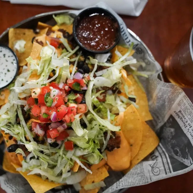 Nachos with cheese, pico, beans, and two accompanying sauces.