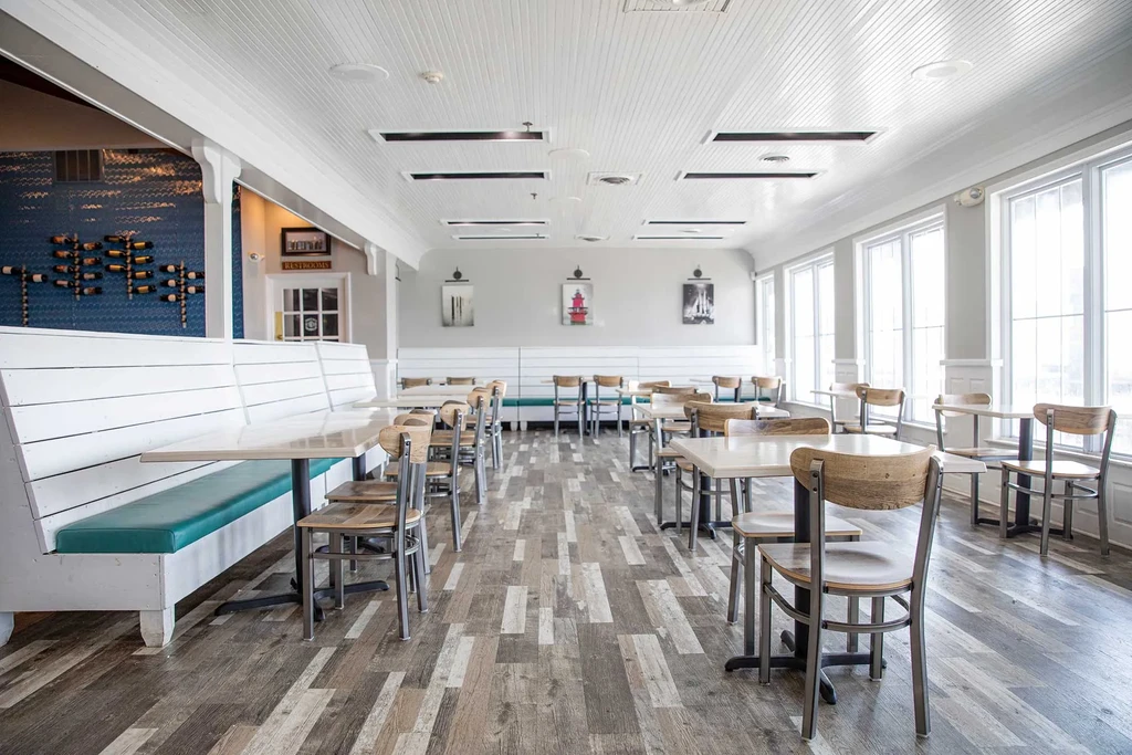 Bright, empty coastal-themed restaurant with teal booths and nautical art.