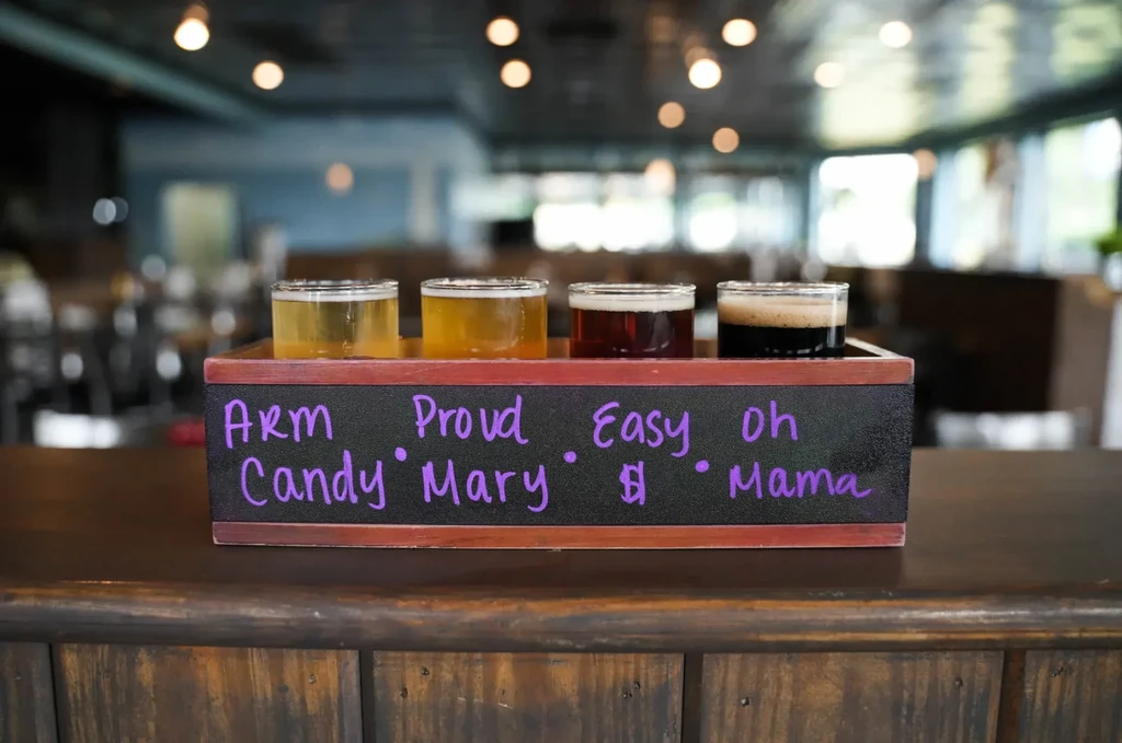 Beer flight of four varied drinks in wooden caddy with chalk.