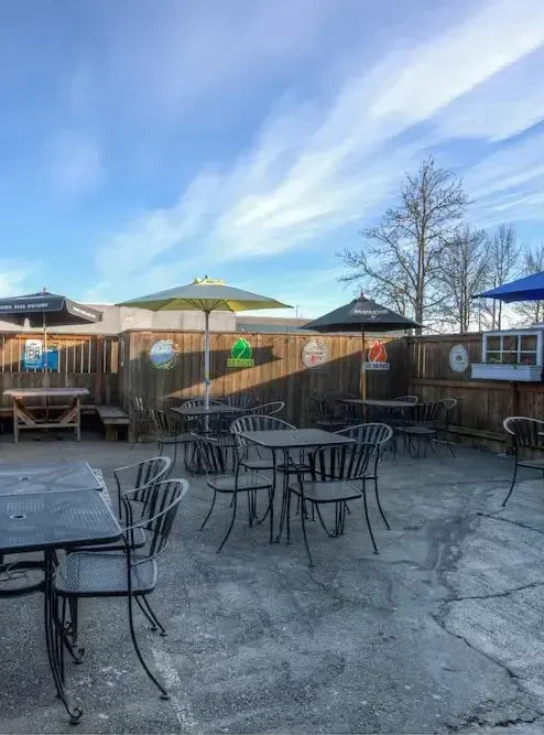Empty outdoor patio with colorful umbrellas, tables, chairs, and branding signs.