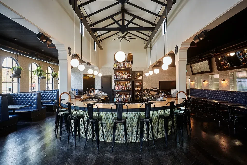 Empty restaurant bar with central wood bar and blue leather booths.