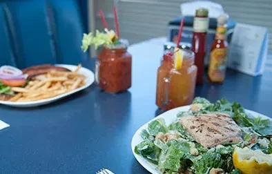 Caesar salad, steak, fries, and two drinks on a casual blue table.