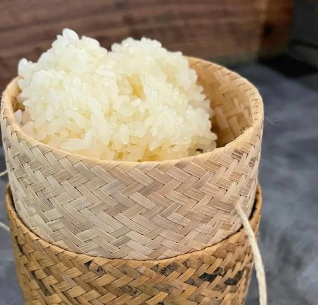 Close-up of fluffy white sticky rice in a traditional woven bamboo basket.