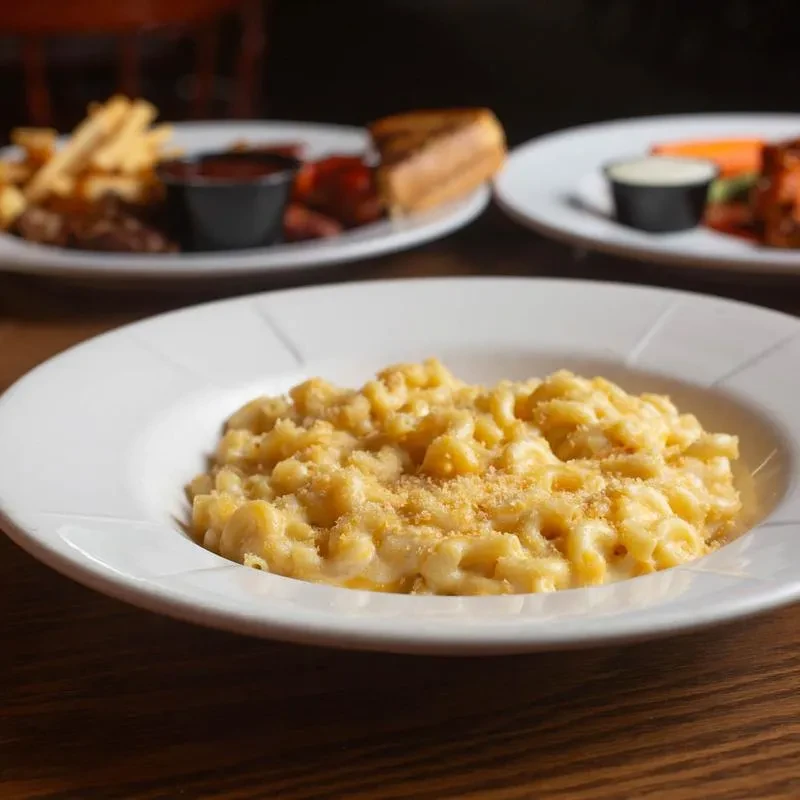 Close-up of golden, creamy macaroni and cheese in a white bowl.