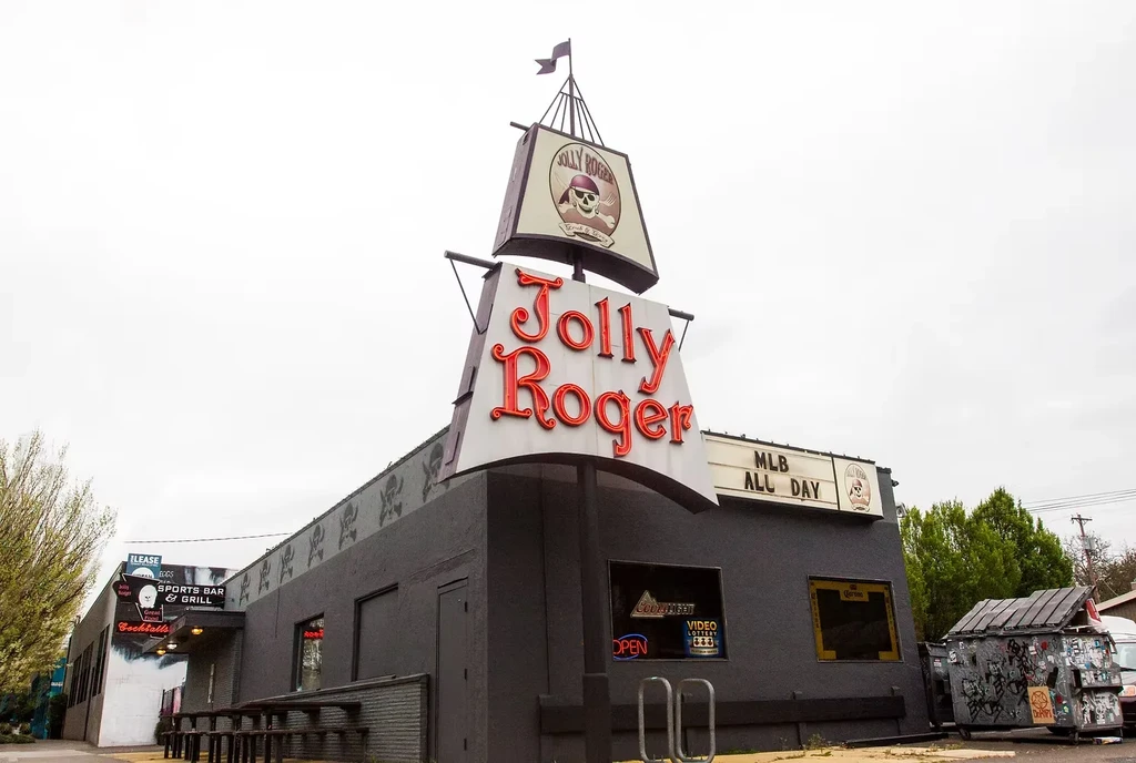 Jolly Roger Sports Bar's dark, pirate-themed exterior with outdoor seating.