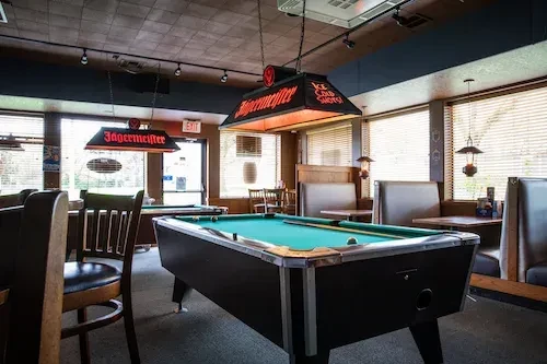 Bar interior with a teal pool table under Jagermeister branded lights.