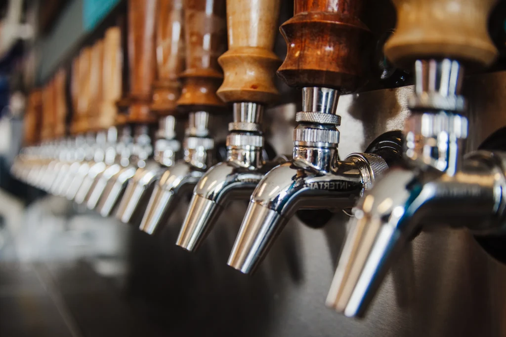 Close-up of shiny chrome beer taps with elaborate wooden handles.