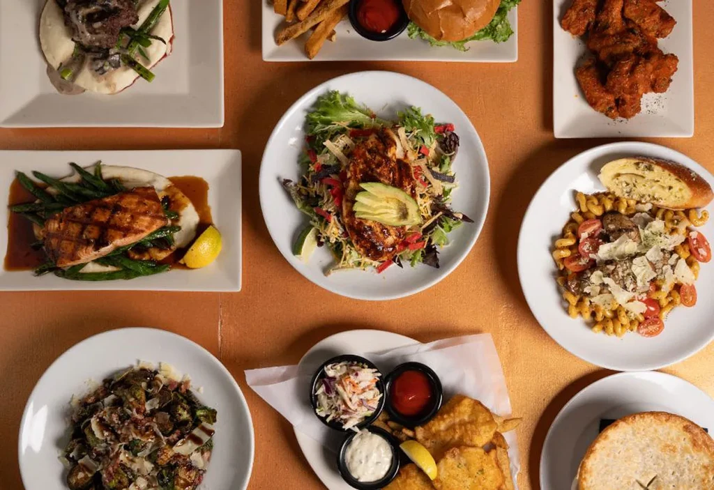 Overhead view of various restaurant dishes, including salmon and pasta.