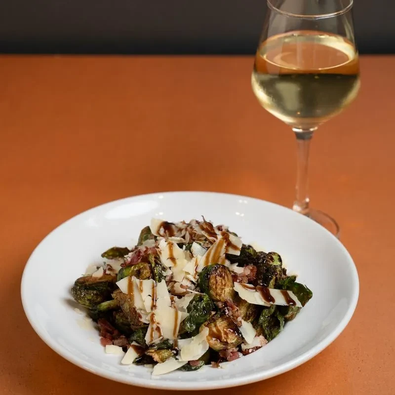 Roasted Brussels sprouts with cheese, bacon, balsamic glaze, and white wine.