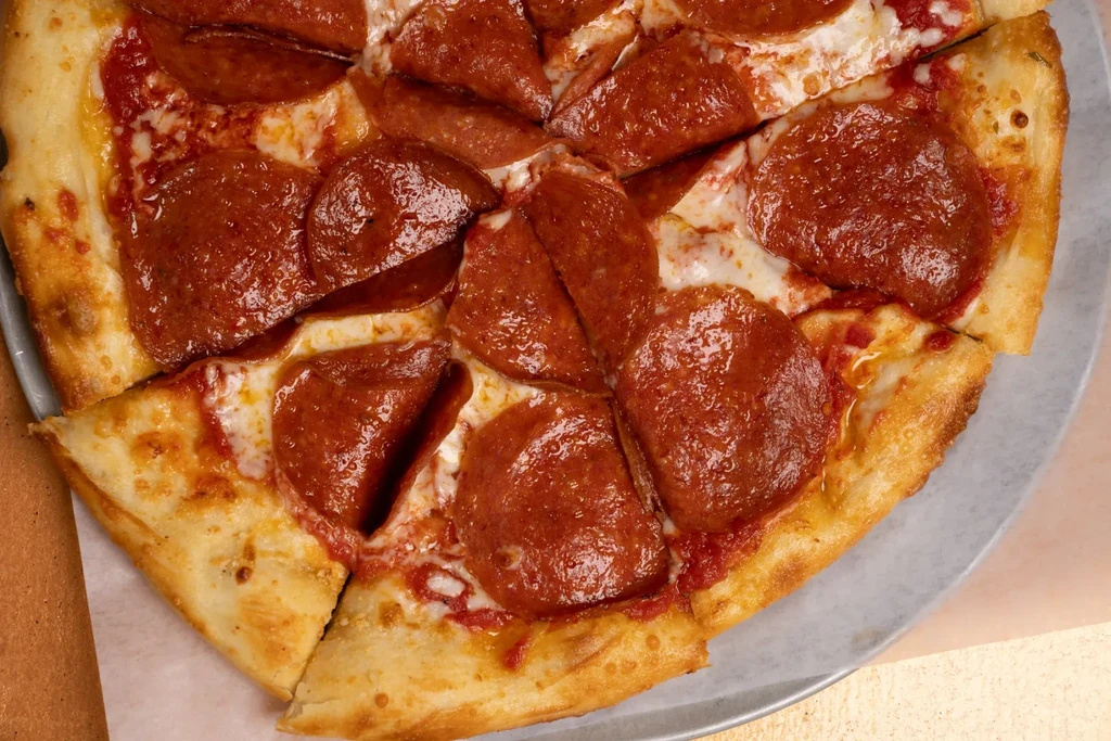 Close-up of a sliced pepperoni pizza with melted cheese on a tray.