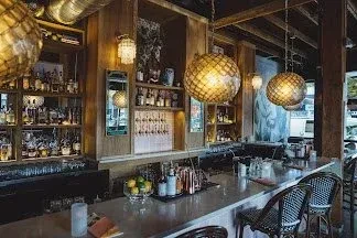 Empty upscale bar with a long counter, liquor, and woven lights.