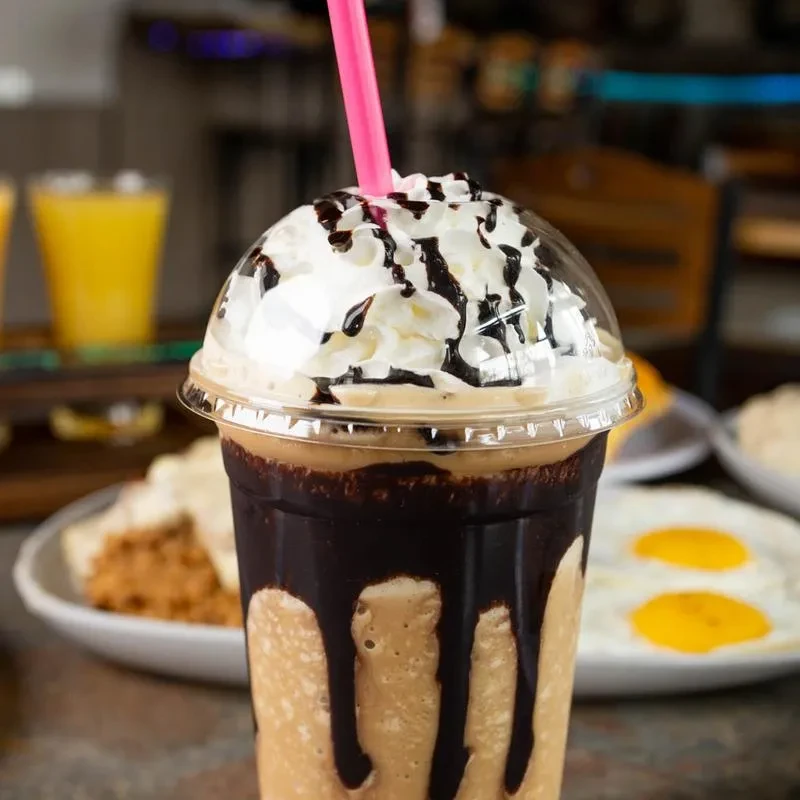A creamy chocolate frappe with whipped cream and pink straw.