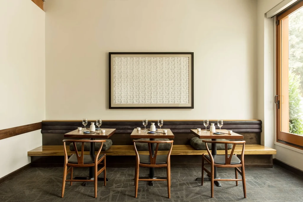 Empty, well-lit restaurant dining room with three tables set.