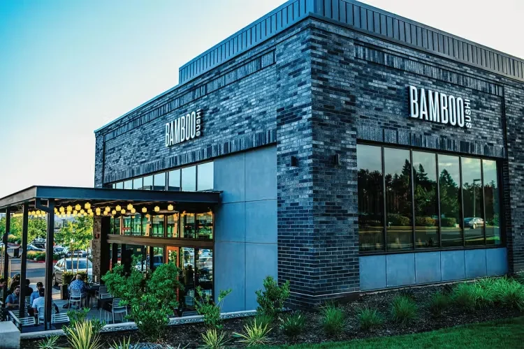 Modern Bamboo Sushi restaurant exterior, illuminated sign, outdoor patio.