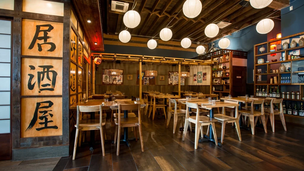 Empty Japanese izakaya interior with paper lanterns and 'Izakaya' calligraphy.
