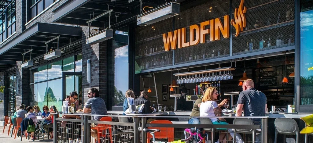WILDFIN restaurant's bright outdoor bar and seating area with customers.