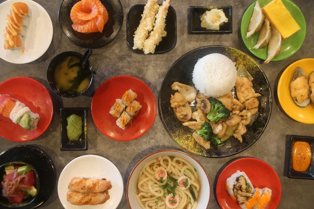 A spread of many diverse Japanese and Asian dishes on a dark table.