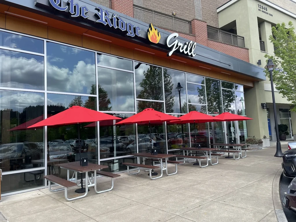 The Ridge Grill exterior with patio, red umbrellas, and window reflections.