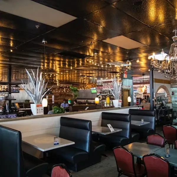 Casual restaurant interior with warm string lights, booths, and a chandelier.
