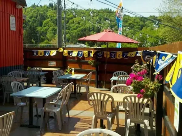 Outdoor patio with tables, Corona flags, green hills, no people.
