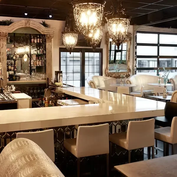 Ornate bar with polished counter, liquor cabinet, chandeliers, tufted sofas.