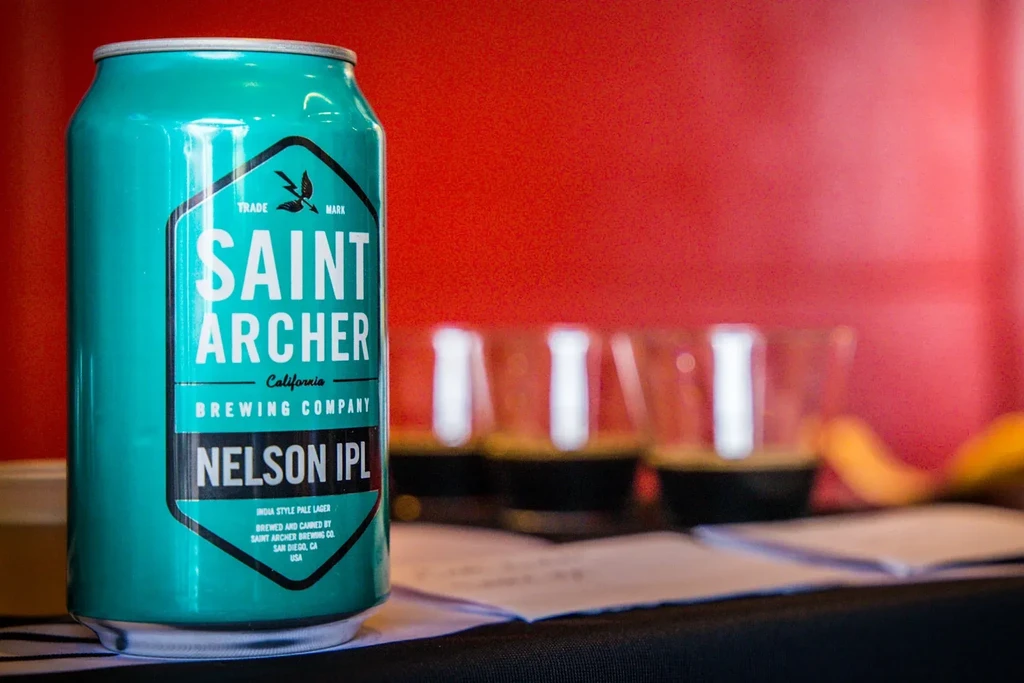 Vibrant teal Saint Archer beer can, lightning bolt logo, vivid red wall.