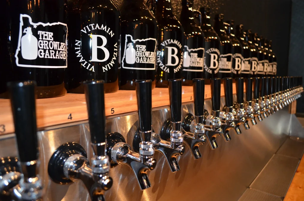 Metallic beer taps and labeled bottles neatly arranged in a bar.
