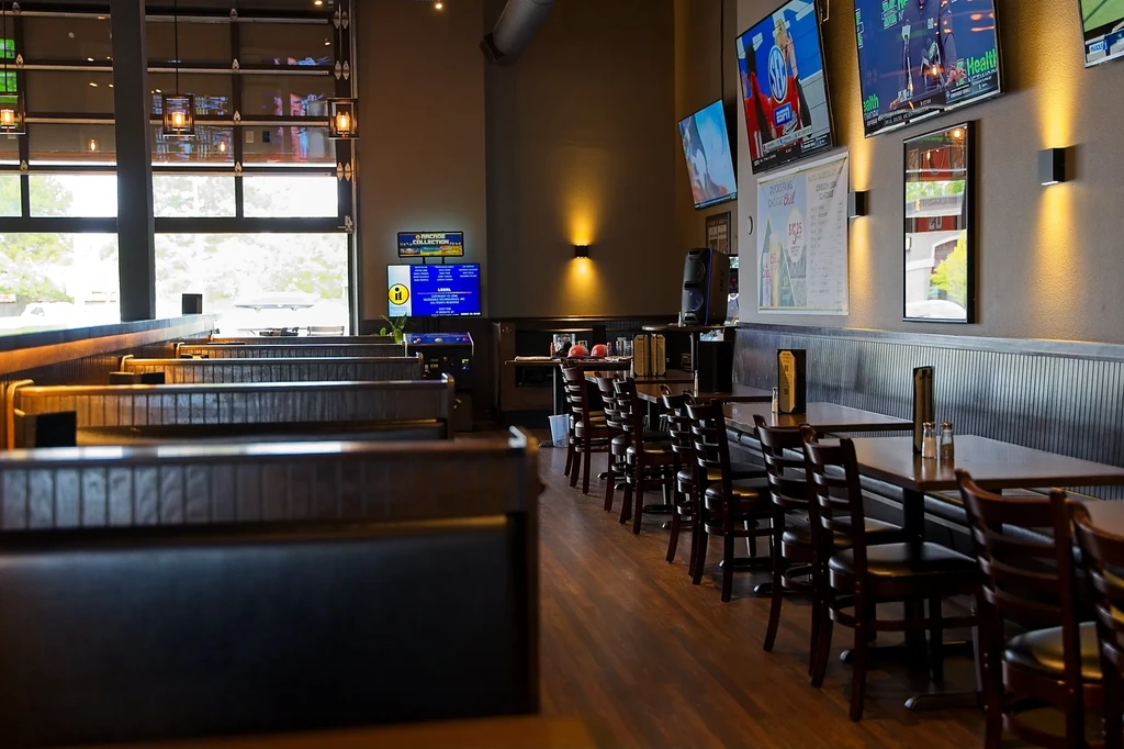 Empty casual sports bar with booths, tables, and sports TVs.