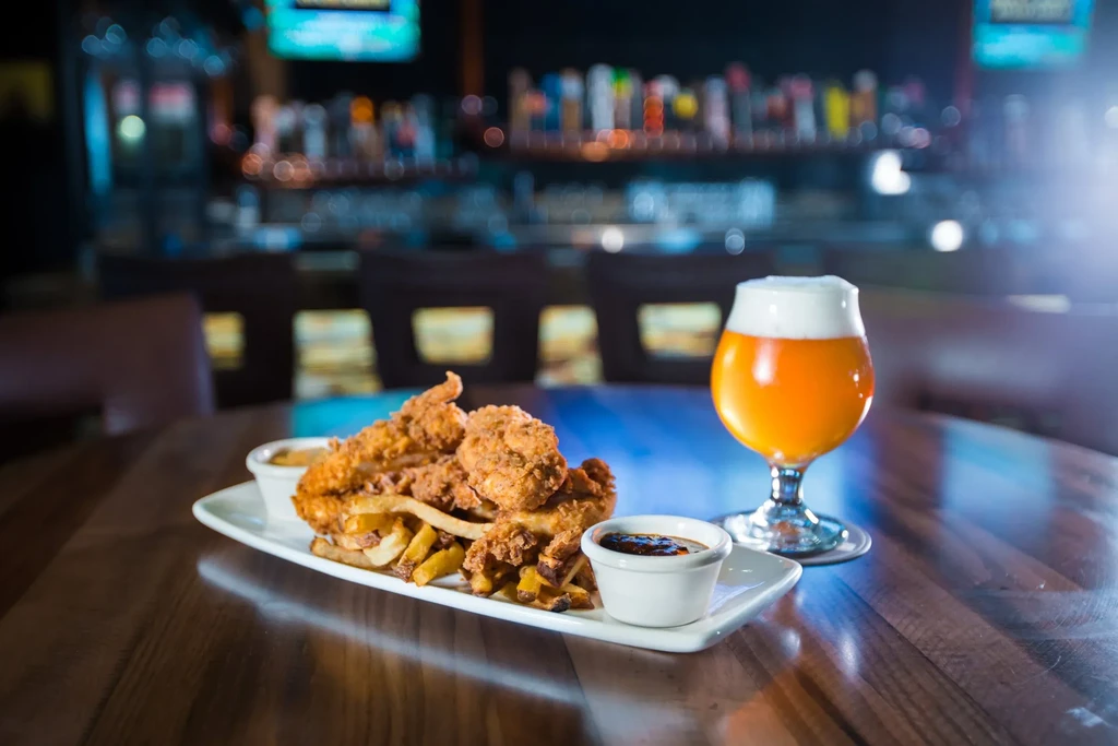 Fried chicken tenders, fries, two dipping sauces, and a beer.