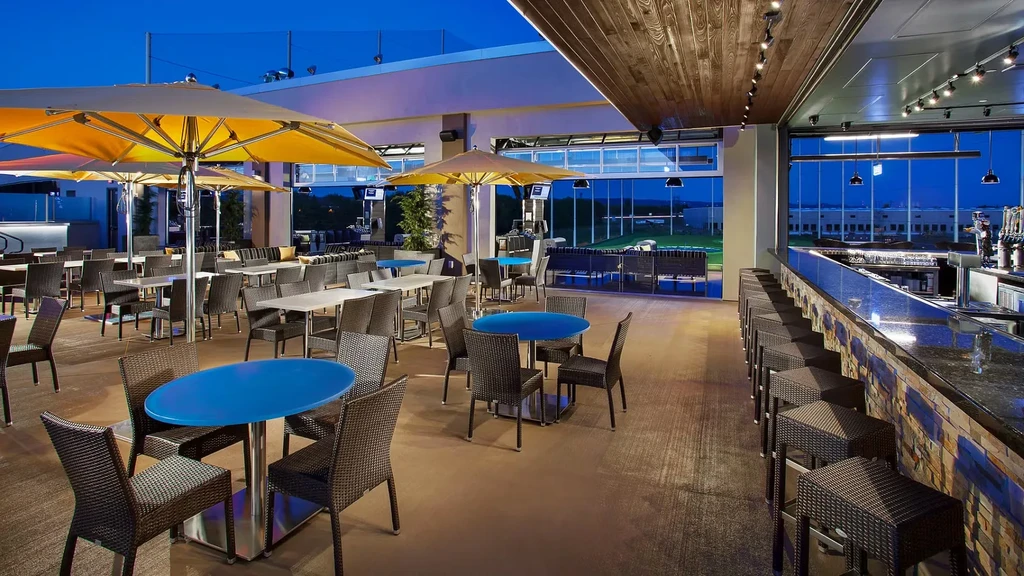 Empty modern outdoor/indoor restaurant and bar overlooks a golf range.