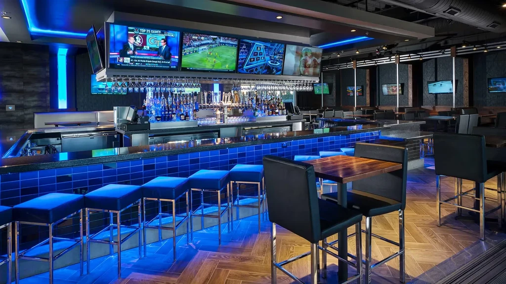 Sleek bar interior featuring blue LED lights, beer taps, and sports screens.