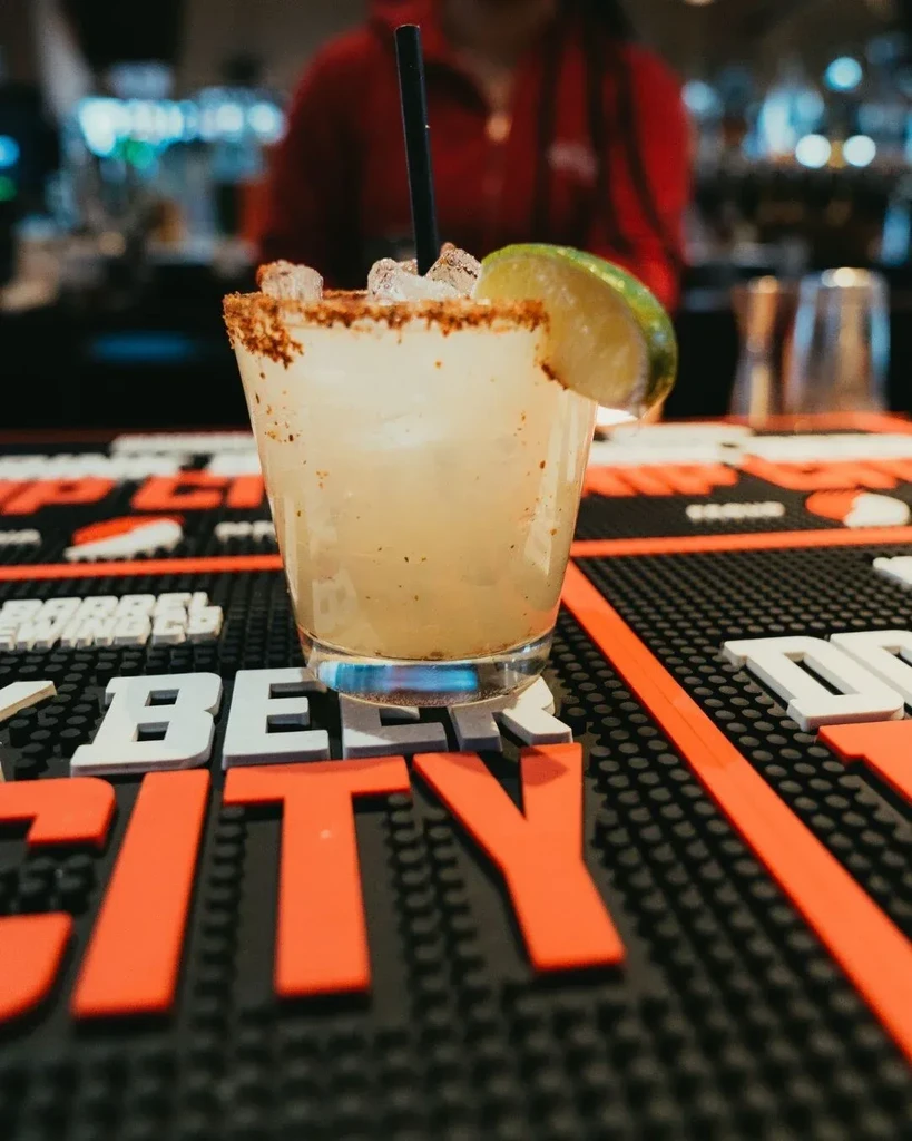 Margarita with lime, ice, and textured rim on a bar mat.
