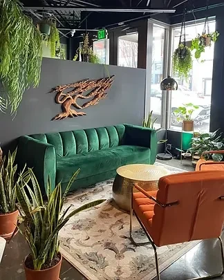 Lounge with emerald velvet sofa, abstract wooden art, abundant plants.