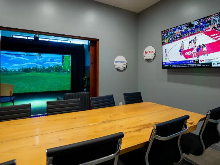 Modern room with live-edge table, golf simulator, and basketball game.