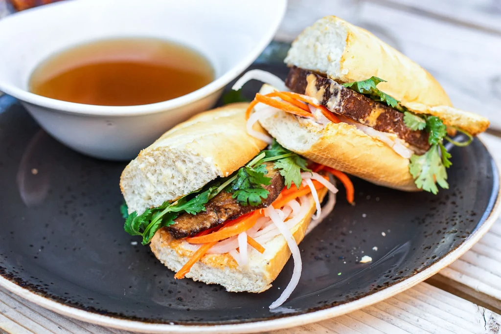 Crusty Banh Mi sandwich halves with cilantro, pickled vegetables, and broth.