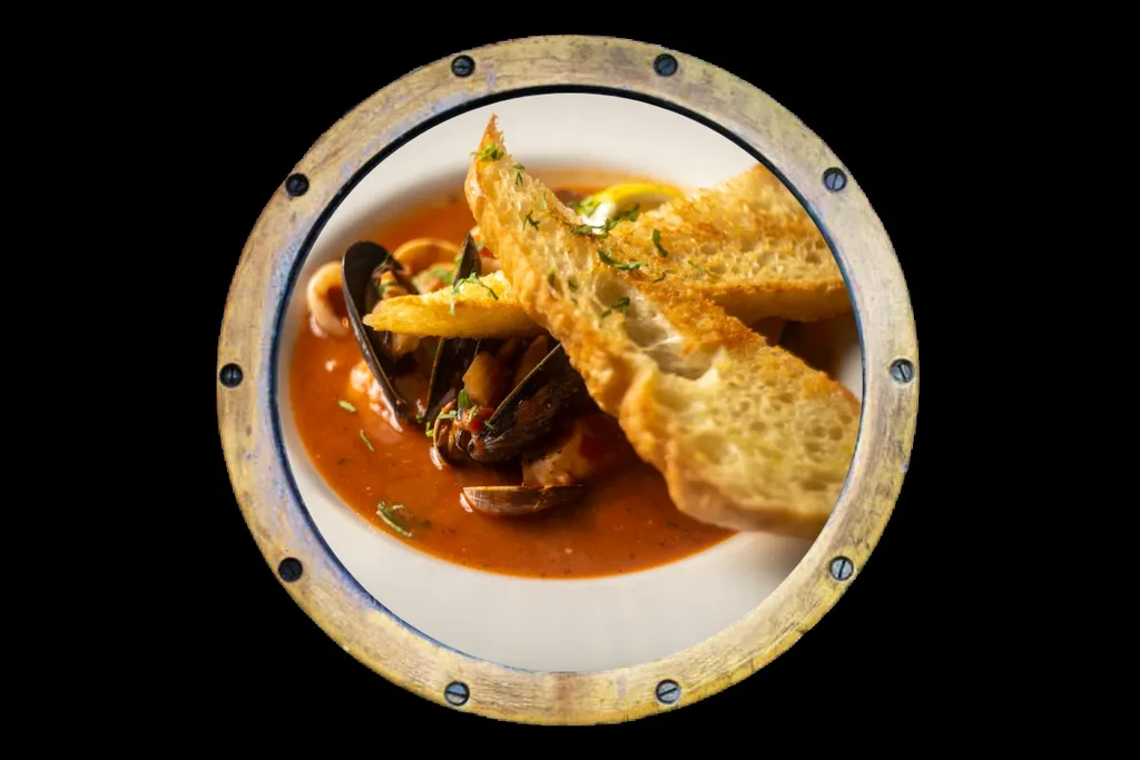 Seafood stew with mussels, toasted bread, viewed through porthole.