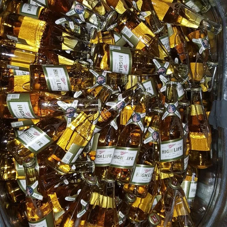 A large pile of full Miller High Life bottles in a container.