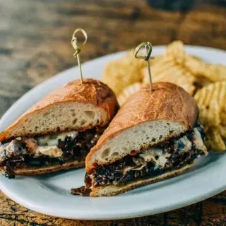 Hearty steak sandwich halves with melted cheese and chips.