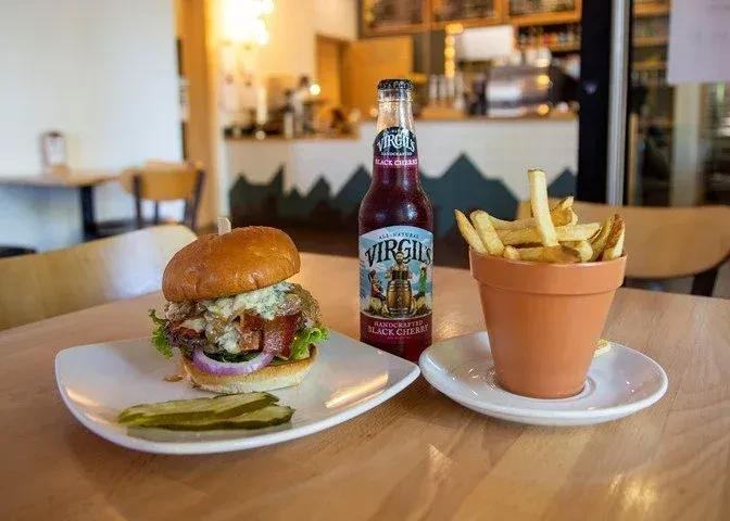Gourmet burger with bacon and blue cheese, fries, and cherry soda.