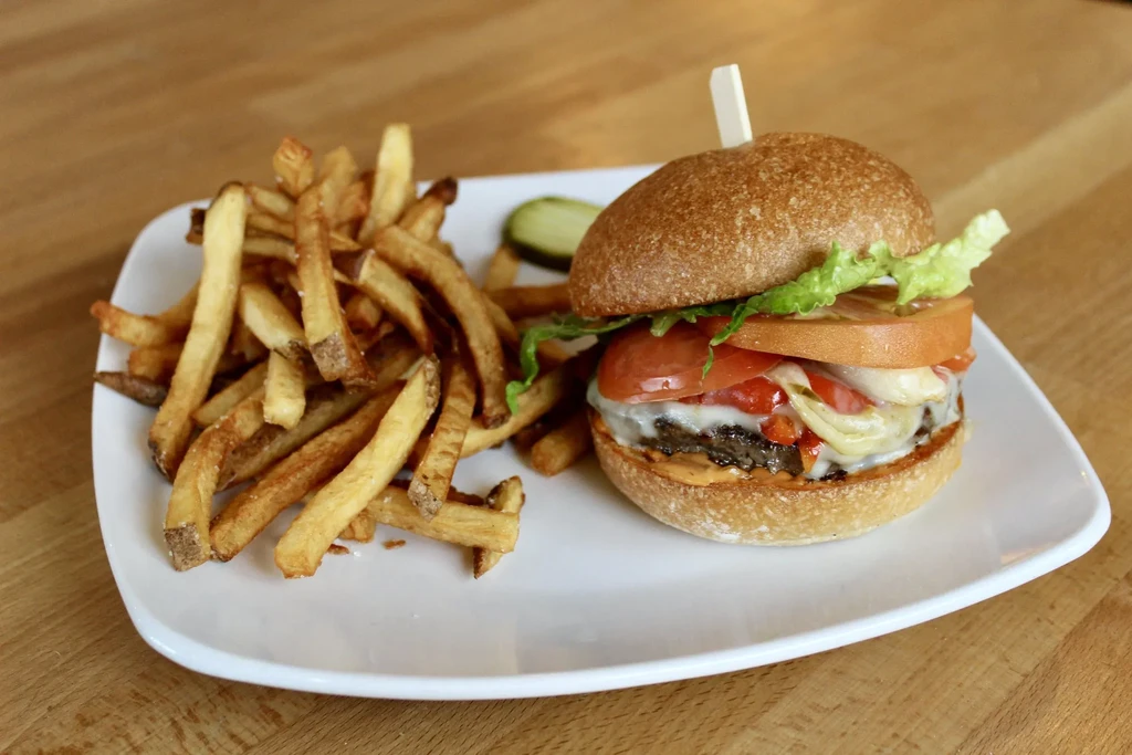 Double-patty cheeseburger with hand-cut fries on a white plate.