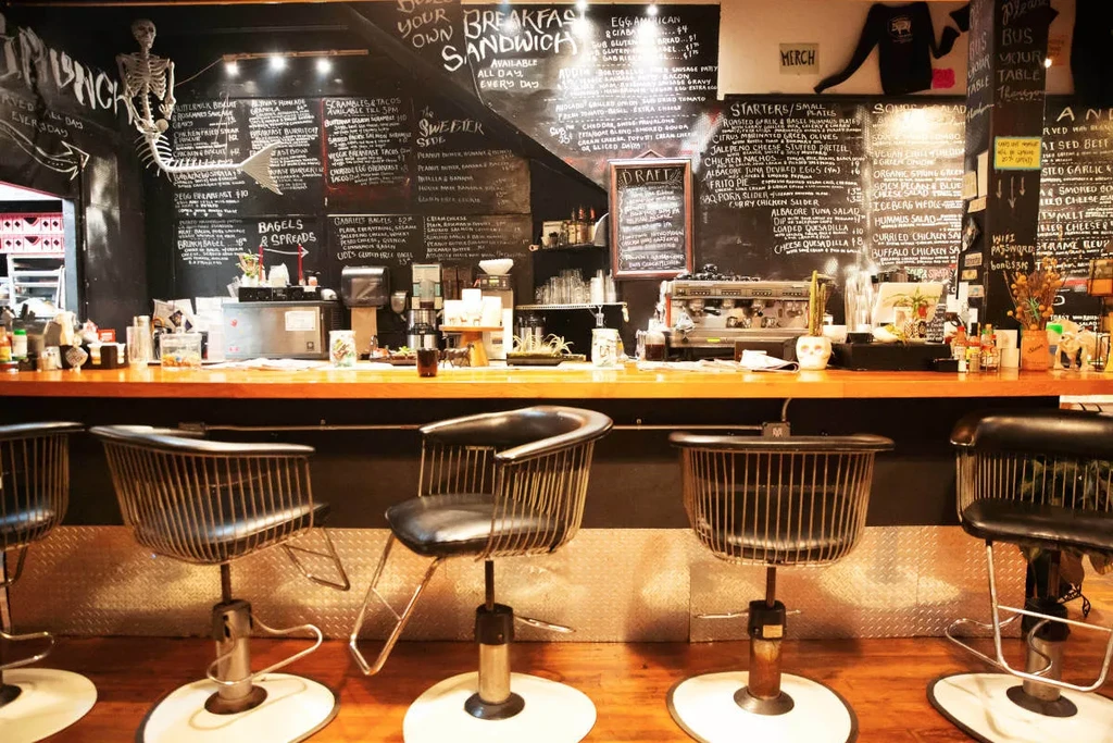 Rustic restaurant interior with wooden counter, chalk menus, and mermaid skeleton.