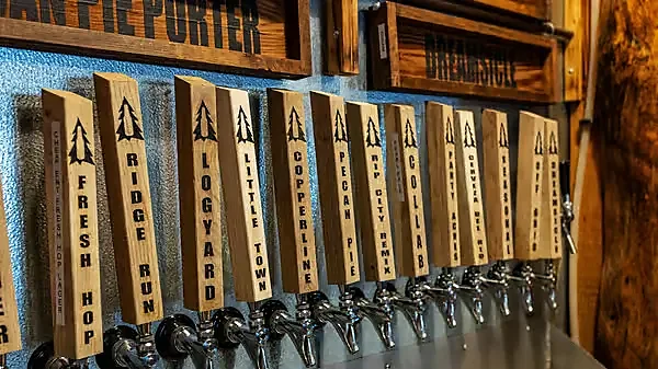 Row of wooden tap handles labeled with house beer names