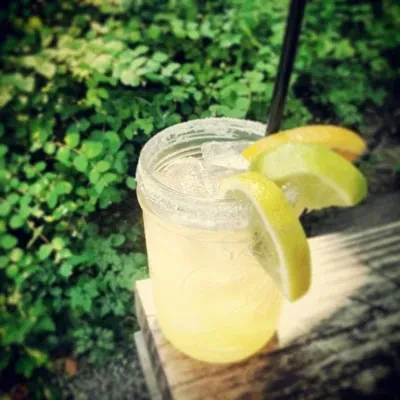 Iced citrus drink in a mason jar on a wooden surface.