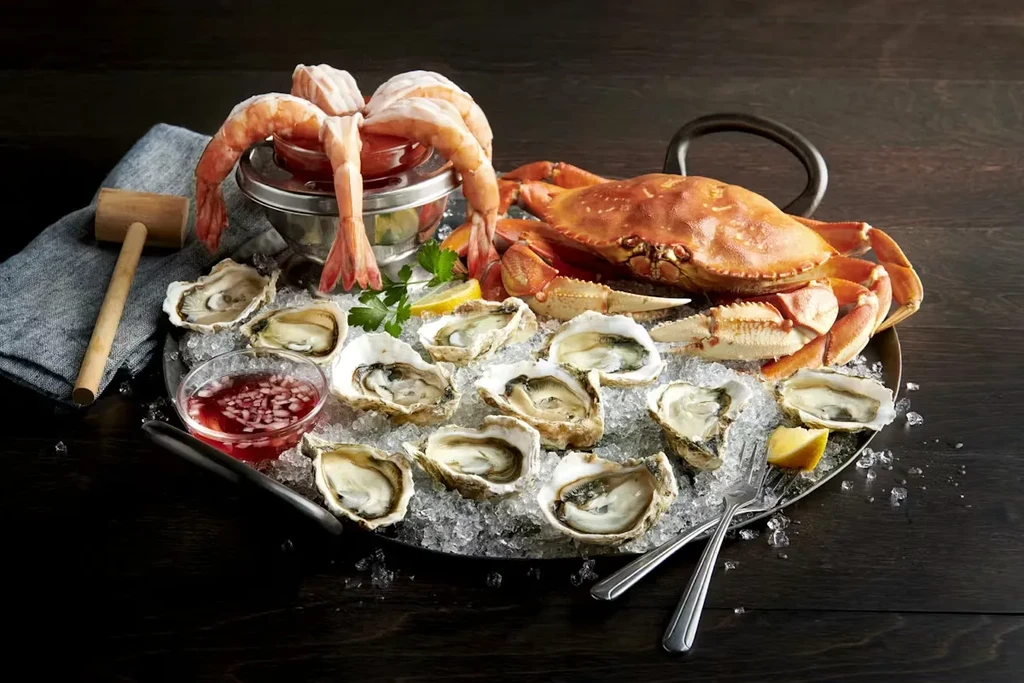 Seafood platter with crab, oysters, and shrimp on crushed ice.