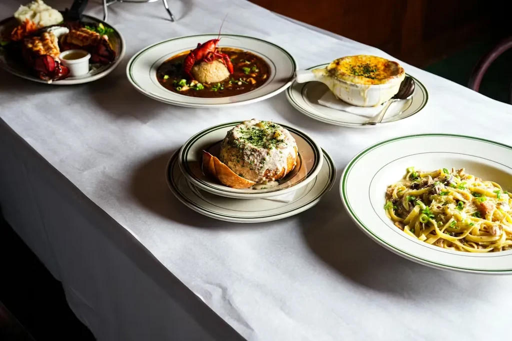 Five varied dishes including seafood, soups, and pasta on a tabletop.